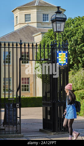 Une étudiante passe devant l'emblème sur la porte à l'entrée de Downing College, Université de Cambridge, en Angleterre. Banque D'Images