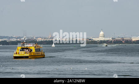 Un taxi de l'eau jaune sur la rivière Potomac se dirige vers Washington, DC. U.S Capitol dome est au centre droit. Banque D'Images