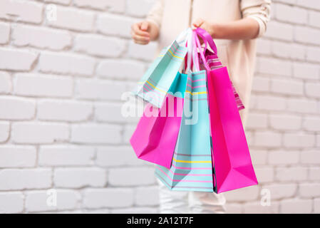 Concept commercial. Girl holding bunch of shopping bags avec les achats près de brick arrière-plan. Copier l'espace. La vente, l'escompte, le black friday concept. Shopping Banque D'Images