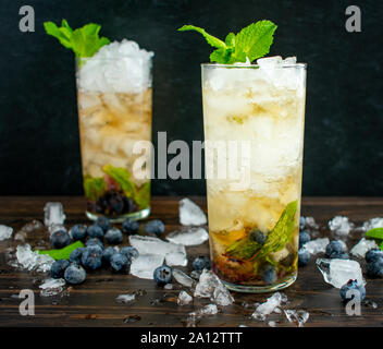 Blueberry Mint Julep Cocktails avec garniture : Deux cocktails à Bourbon whiskey, bleuets, et des feuilles de menthe sur la glace concassée Banque D'Images