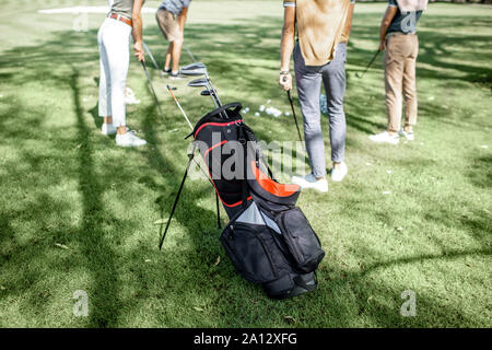 Sac de golf plein de putters sur la pelouse verte avec des gens jouer au golf sur l'arrière-plan Banque D'Images