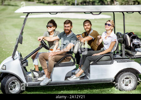 Portrait d'un groupe de jeunes amis s'amuser tout en conduisant une voiture de golf sur les terrains de stage sur une journée ensoleillée Banque D'Images