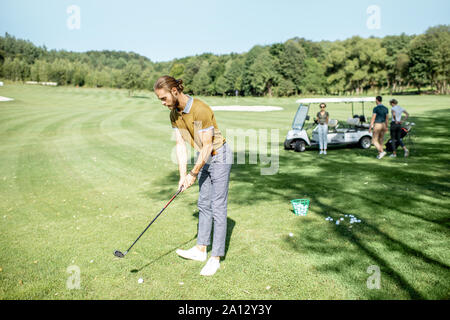 L'homme jouant le golf, se balancer avec le putter sur un beau parcours sur une journée ensoleillée Banque D'Images