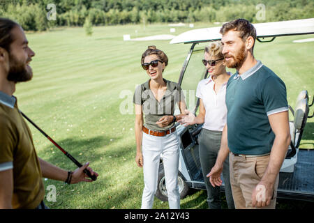 Un groupe de jeunes professionnels amis rassemblement devant le jeu de golf près de la voiture sur un parcours à jouer sur une journée ensoleillée Banque D'Images