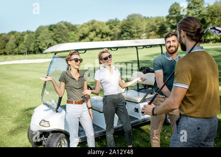 Un groupe de jeunes professionnels amis rassemblement devant le jeu de golf près de la voiture sur un parcours à jouer sur une journée ensoleillée Banque D'Images