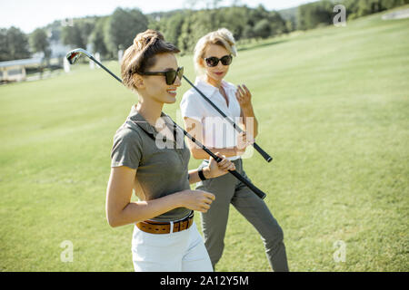Les deux meilleurs amis de marcher tout en jouant un jeu de golf putters pendant sur un cours sur une journée ensoleillée Banque D'Images