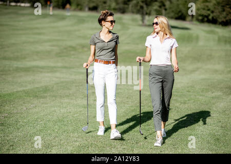 Les deux meilleurs amis de marcher avec le matériel de golf sur le magnifique parcours de jeu, parler et s'amuser lors d'un jeu sur une journée ensoleillée Banque D'Images
