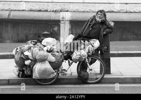 Un SANS-ABRI DANS LES RUES DE LONDRES AVEC SES EFFETS PERSONNELS TRANSPORTÉS ENSEMBLE DANS DES SACS EN PLASTIQUE SUR UN CYCLE. Les sans-abri A DONNÉ SON ACCORD POUR CETTE PHOTOGRAPHIE À PRENDRE DE LUI. Le pauvre homme A DIT QU'IL AVAIT VÉCU DANS LA RUE PENDANT QUATRE ANS [ 4 ]. Banque D'Images