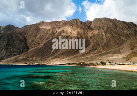 Lagon avec une barrière de corail sur fond de hautes montagnes et un ciel bleu avec des nuages blancs en Egypte Dahab Banque D'Images