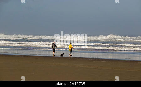 Un couple d'âge moyen et leur petit chien dérive de l'océan Pacifique dans la plage vide, Bandon, Oregon Oregon le long de la côte du Pacifique. Banque D'Images