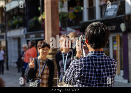 Les jeunes de la Chine tourisme taking photo of two smiling asian girls dans la rue de Chester, tenant deux appareils photo dans sa main. Banque D'Images