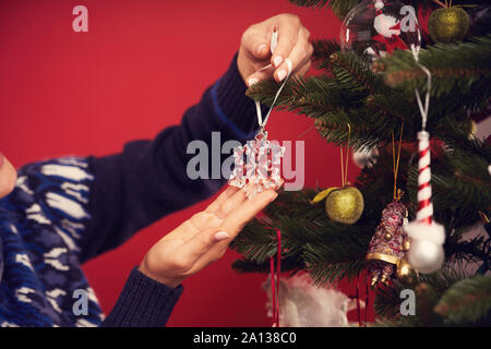 Hot woman decorating Christmas Tree sur fond rouge Banque D'Images