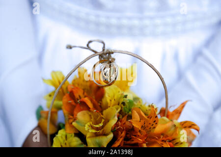 Enfant hands holding bouquet avec les anneaux de mariage, le détail de la main de de demoiselle d'arrangement avec la tenue de mariage, les alliances, les bijoux, rejoint han Banque D'Images