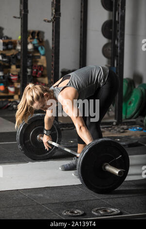 Jeune femme forte préparez à soulever de lourdes barbell dans une salle de sport. Banque D'Images