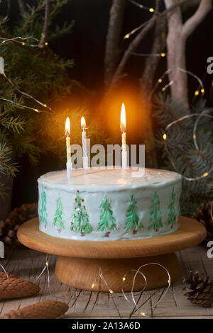 Gâteau de célébration décorées de sapins de Noël sur un fond sombre de branches et de cônes. Style rustique. Banque D'Images