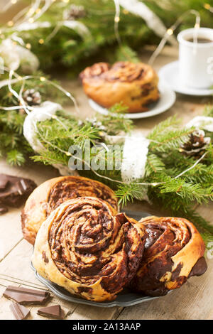 Muffins au chocolat escargot servi avec du café sur l'arrière-plan d'une couronne de branches de sapin et les cônes. Style rustique. Banque D'Images