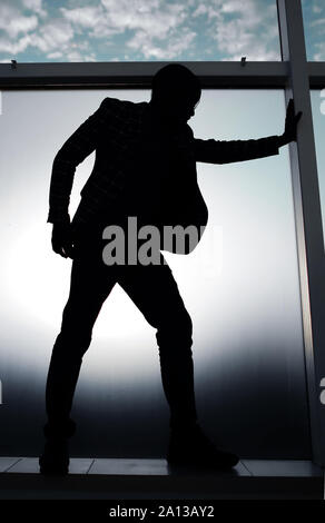 Silhouette d'un homme debout près de la fenêtre du bureau Banque D'Images