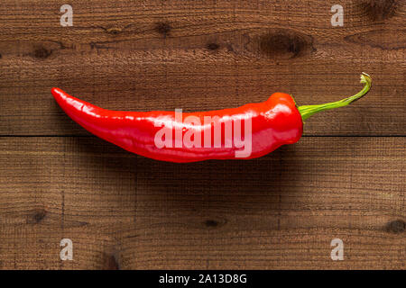 Une nouvelle banane rouge poivre sur un fond de bois foncé texturé Banque D'Images