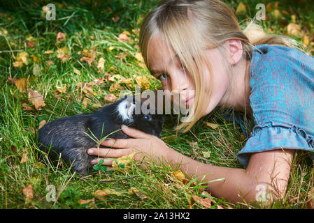 Enfant mignon fille jouant avec l'animal de compagnie cobaye à l'extérieur sur herbe verte Banque D'Images