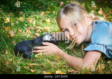 Enfant mignon fille jouant avec l'animal de compagnie cobaye à l'extérieur sur herbe verte Banque D'Images