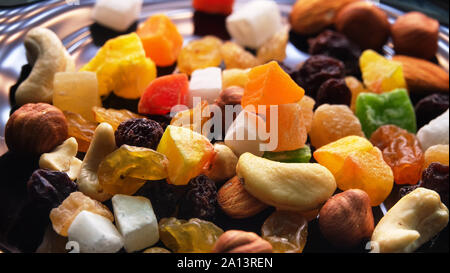 Tutti frutti. Mélange de fruits secs (raisins, citron, mangue) et les noix (amandes, noisettes) sur un plat laqué noir Banque D'Images