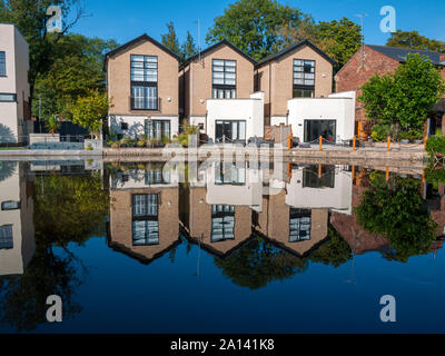 Un développement de trois maisons côté canal appelé 'le chantier' reflète dans le canal Ashton, Audenshaw, Tameside, Manchester, Angleterre, Royaume-Uni. Banque D'Images