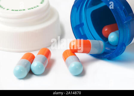 Capsules bleu et orange bleu avec flacon de médicaments sur blanc. Banque D'Images