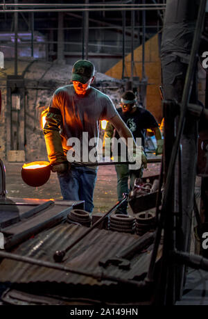 27 Sept 2019 Kokomo Indiana USA ; creuset des louches de pâte de verre sont effectuées par les travailleurs d'une autre machine qui, à son tour, cette forme liquide incandescent Banque D'Images