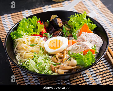 Soupe ramen japonais avec du poulet, des œufs, des aubergines et champignons shimeji sur fond de bois sombre. Chanko nabe, soupe de sumo. Banque D'Images