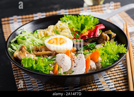 Soupe ramen japonais avec du poulet, des œufs, des aubergines et champignons shimeji sur fond de bois sombre. Chanko nabe, soupe de sumo. Banque D'Images