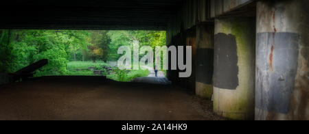 Femme de marcher sous pont de l'autoroute le long de Chesapeake and Ohio Canal encadré par le pont Banque D'Images