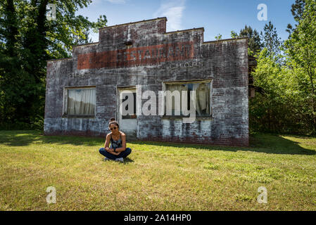 Femme Asiatique avec des lunettes assis en face des bâtiments délabrés et abondoned restaurant en Virginie Banque D'Images
