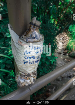 Bouteille en plastique avec un message "Merci de prendre soin de notre planète" rempli de mégots de cigarettes. Idée d'empêcher la pollution de l'environnement. Banque D'Images