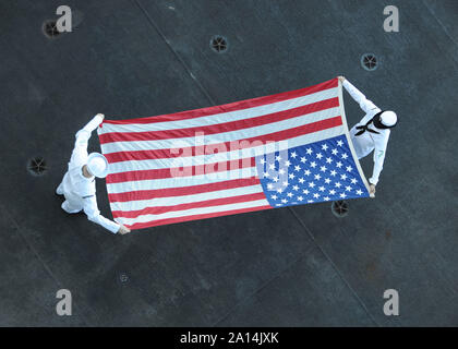 Ordnancemen Aviation plier le drapeau américain à bord du USS Theodore Roosevelt. Banque D'Images