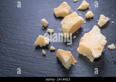 Close up de savoureux morceaux frais fromage parmigiano sur fond d'ardoise noire Banque D'Images