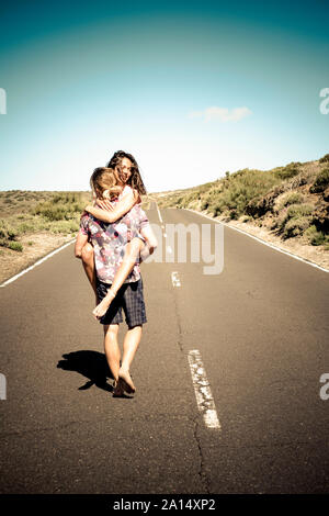 Happy young couple in love marcher ensemble sur une longue route droite - homme rire cheerful woman - concept de voyager ensemble et s'amuser Banque D'Images