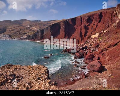 Montagnes rouge vif inhabituelle sous ciel bleu et turquoise de l'eau sur la plage de Kokkini Red Santorini Grèce Banque D'Images