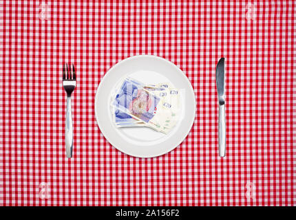 Livre sterling GBP 20 notes billets sur une plaque blanche avec fourchette et couteau vue aérienne Banque D'Images
