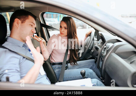 Auto mâle formateur prend l examen en jeune femme. Étudiante regardez enseignant avec la confusion et les malentendus. Guy show mains et regarder vers le bas. Dayl Banque D'Images