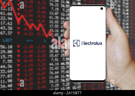 Un homme est titulaire d'un smartphone affichant le logo de la société Electrolux énumérés sur OMX Stockholm. Contexte du marché boursier négatif. Credit : PIXDUCE Banque D'Images
