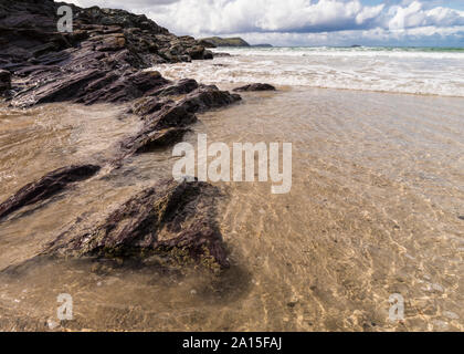 Marée montante sur la plage à Hayle Bay, Cornwall, Angleterre Royaume-uni sur une journée ensoleillée avec des rochers et des vagues. Banque D'Images