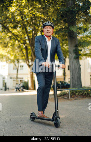 Hauts homme monté sur l'e-scooter dans la ville Banque D'Images