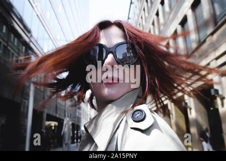 Portrait d'une femme élégante avec des lunettes de soleil et imperméable Banque D'Images
