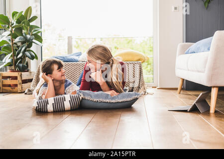 Mère et fille se trouvant sur le plancher à la maison à l'un l'autre Banque D'Images