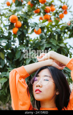 Portrait of young asian woman, la mandarine arbre dans l'arrière-plan Banque D'Images