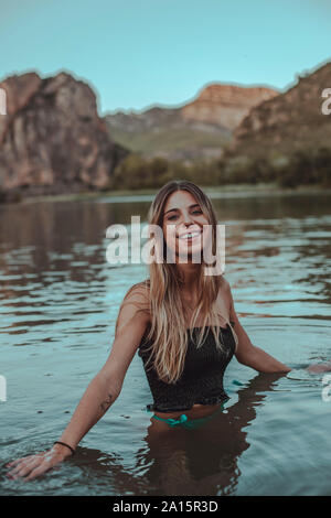 Jeune femme blonde se baignant dans un lac en été, dans la soirée Banque D'Images