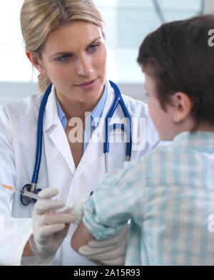 Femme médecin donnant un jeune garçon d'une vaccination à la clinique Banque D'Images