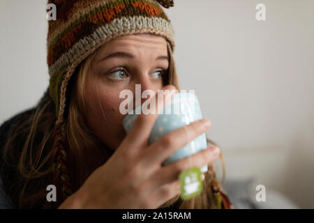 Mauvais jeune femme à boire le thé au lit à la maison Banque D'Images