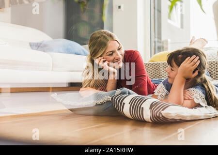 Mère et fille se trouvant sur le plancher à la maison à l'un l'autre Banque D'Images