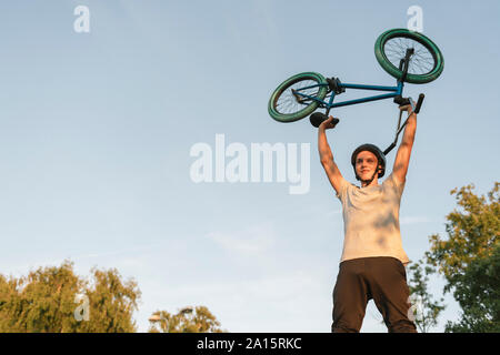 Jeune homme soulevant vélo BMX Banque D'Images